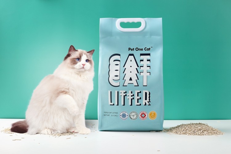A white cat standing next to a bag of cat food.