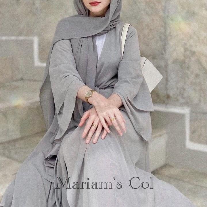 A woman wearing a grey hijab sitting on steps.