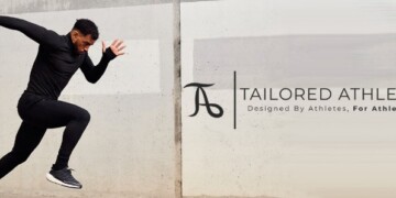 Man in black athletic wear sprinting by a concrete wall, with the logo and slogan "tailored athlete - designed by athletes, for athletes" on the right.